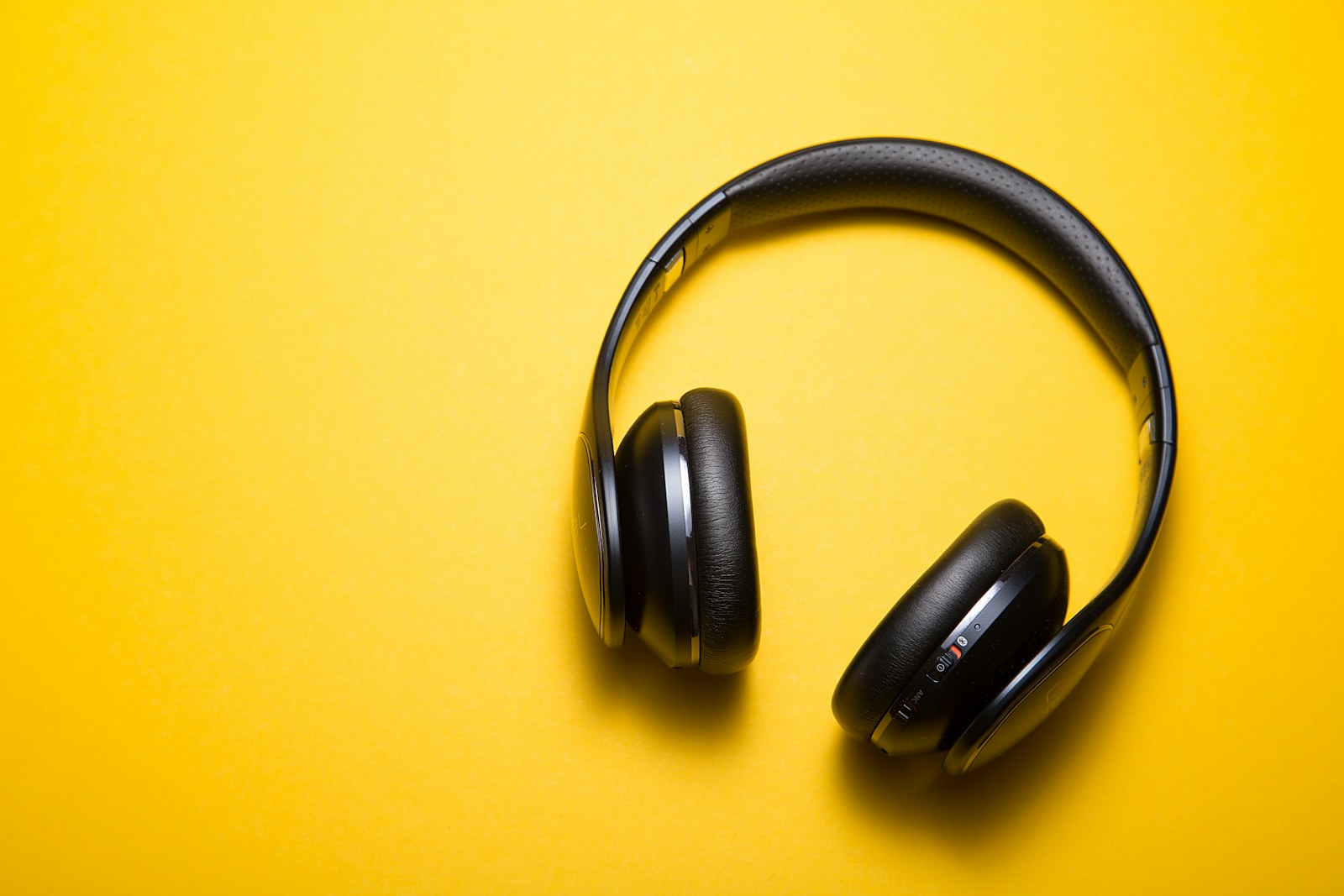 Black over-ear headphones on a yellow background